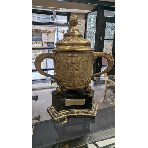 269 - A silver three handle cup approx 1138 grams on wooden plinth, the cup is hallmarked Chester 1902 by ... 