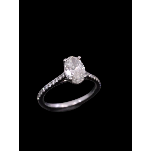 153 - An oval diamond solitaire ring set with diamond shoulders with a valuation which states the diamond ... 