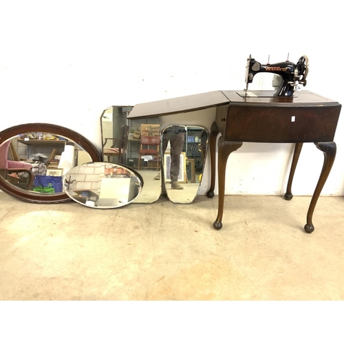 A Vickers sewing machine in fitted table, with three frameless mirrors