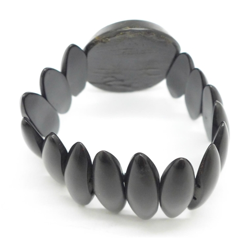 1002 - A Victorian Whitby jet bracelet set with a carved oval panel, (panel 5cm, possibly bog oak)