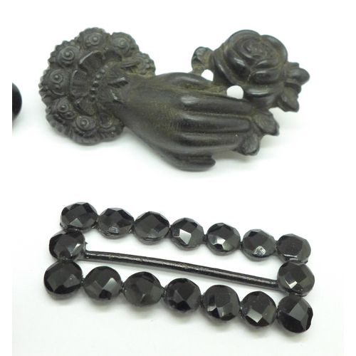 1005 - A jet bracelet with book charm, requires fastener, four carved brooches, one lacking pin, and a buck... 