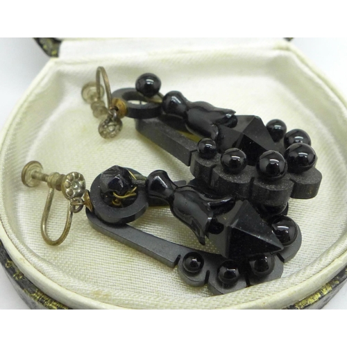 1007 - A Whitby jet faceted bead necklace, a pair of Whitby jet earrings and four black carved brooches