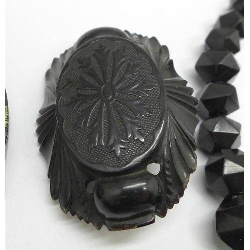 1007 - A Whitby jet faceted bead necklace, a pair of Whitby jet earrings and four black carved brooches