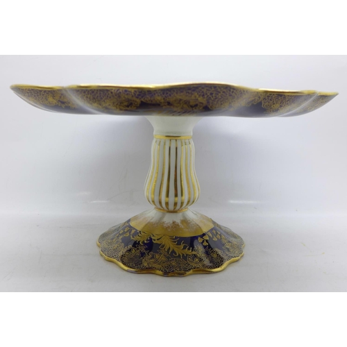 792 - An Aynsley tazza, with a blue and gold border and decoration, having a central hand painted landscap... 