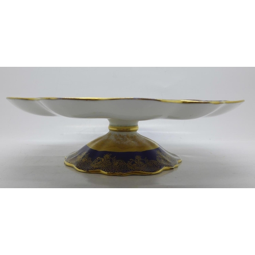 794 - An Aynsley tazza, with a blue and gold border and decoration, having a central hand painted landscap... 