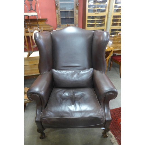 77 - A large mahogany and brown leather wingback armchair