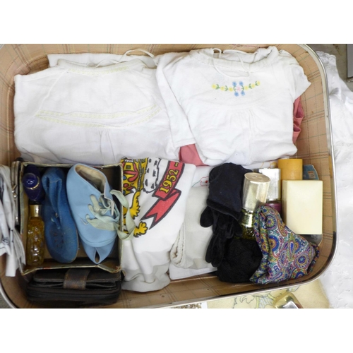 699 - A suitcase containing clothing, babywear, gloves, Christening gowns, etc.