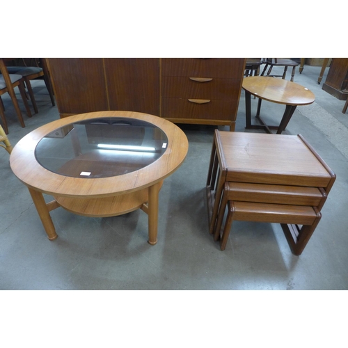 105 - A teak and glass topped circular coffee table and a nest of tables