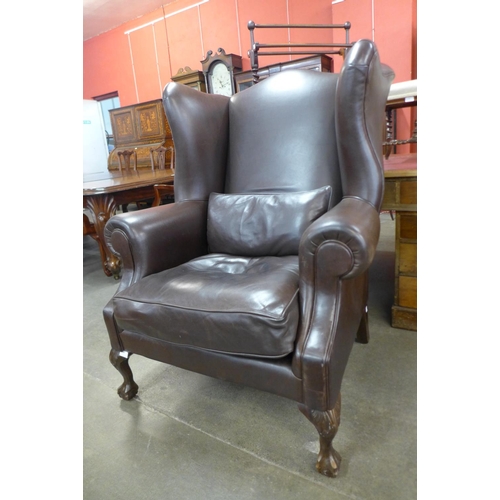 77 - A large mahogany and brown leather wingback armchair