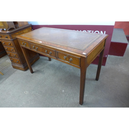 83 - A walnut leather topped three drawer writing table