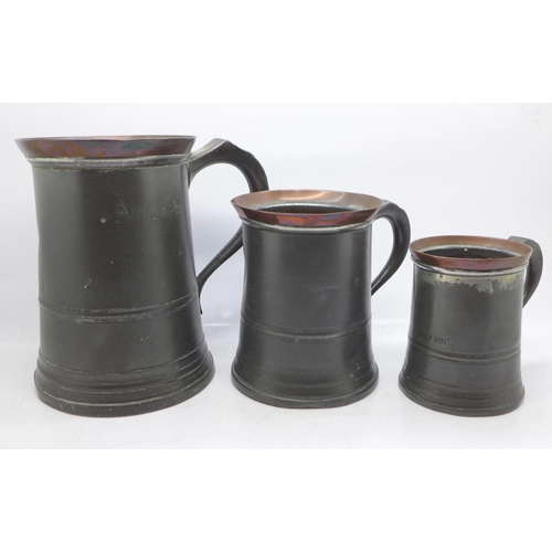 603 - A set of three pewter and copper graduated mugs, Quart, Pint and Half-Pint, marked GR