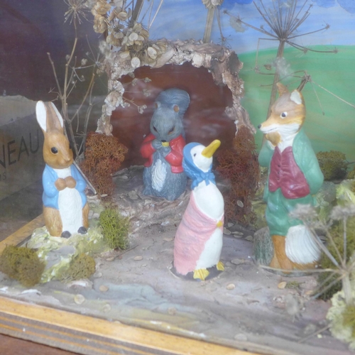 681 - A Beatrix Potter Peter Rabbit shop display diorama containing eight figures, in a glass display case... 