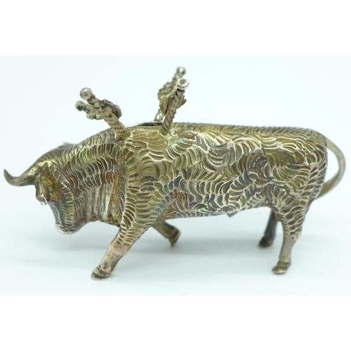 856 - A white metal stand in the form of a bull with six small swords/olive sticks, length 7.5cm