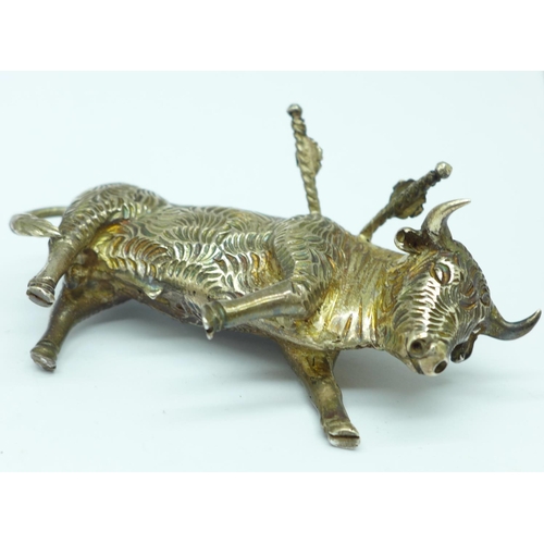 856 - A white metal stand in the form of a bull with six small swords/olive sticks, length 7.5cm