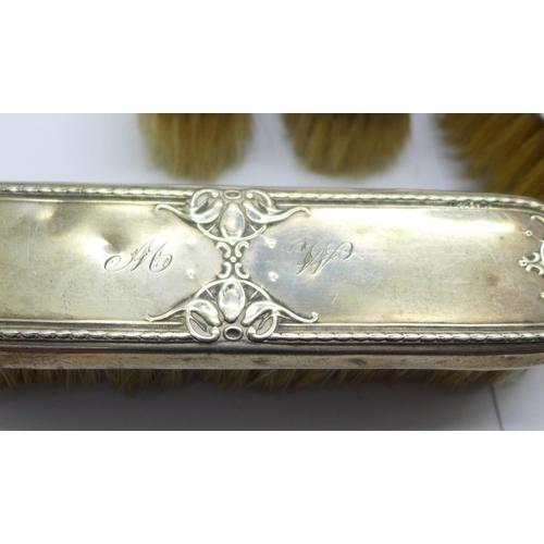 851 - A silver backed hand mirror and four brushes