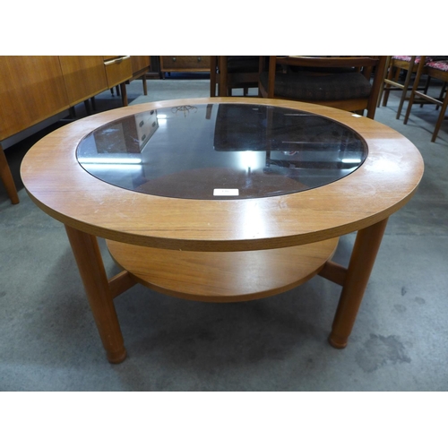 136 - A teak and glass topped circular coffee table