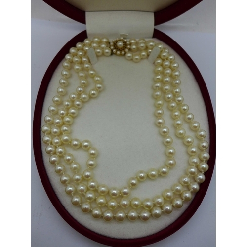 935 - A three-strand pearl necklace with 9ct gold clasp set with garnets, cased