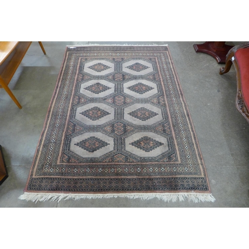 188 - An eastern terracotta ground rug, 174 x 126cms