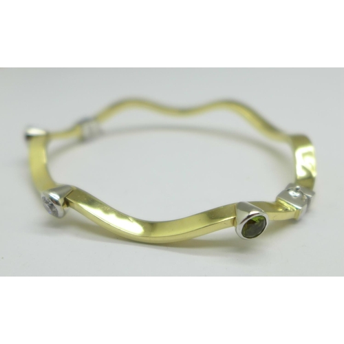 1056 - A 14ct gold, peridot and white sapphire bangle, 9.0g