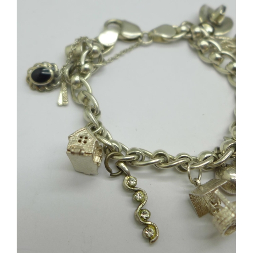 1060 - A silver charm bracelet with twelve charms, 40g, (one charm not silver)