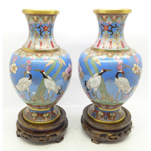 643 - A pair of cloisonne vases decorated with storks, on wooden stands, 19cm