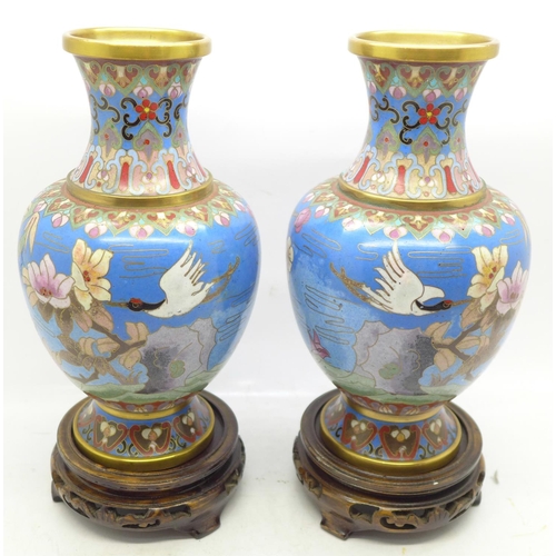 643 - A pair of cloisonne vases decorated with storks, on wooden stands, 19cm