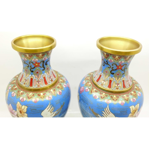 643 - A pair of cloisonne vases decorated with storks, on wooden stands, 19cm