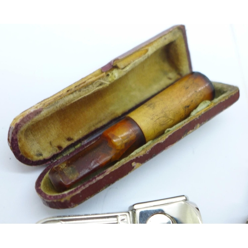 860 - Two cigar cutters and two amber cheroot holders, cased, one with 9ct gold rim a/f