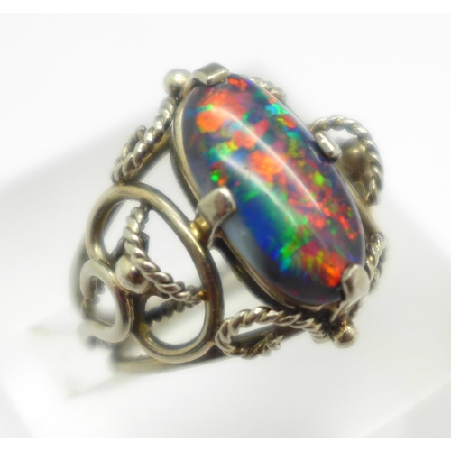 999 - An oval cabochon cut black double opal set ring, in a white metal Arts and Crafts style setting, opa... 