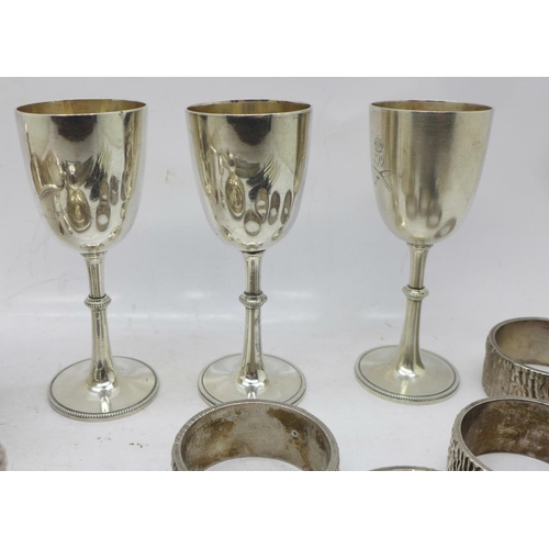 692 - Three small plated goblets with crossed kukri emblem, a plated chamber stick, four napkin rings, a p... 