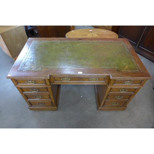 76 - A Victorian oak and green leather topped pedestal desk