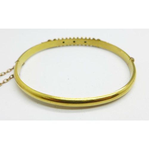 1062 - A 15ct gold and three stone set bangle with box, 7.4g