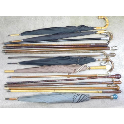 814 - A collection of sixteen walking sticks and umbrellas, three with silver tops, one with 18ct gold dec... 