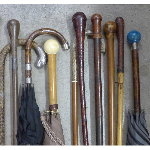 814 - A collection of sixteen walking sticks and umbrellas, three with silver tops, one with 18ct gold dec... 