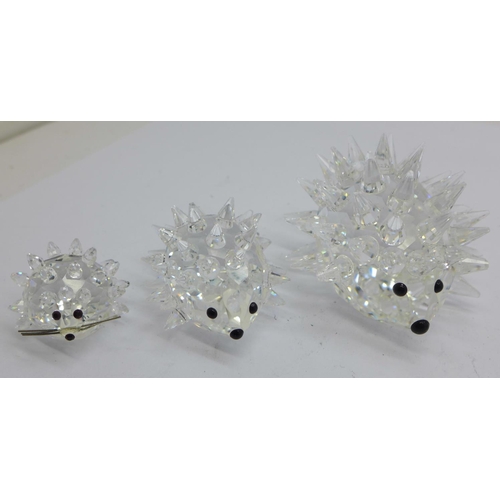 875 - Three Swarovski hedgehogs, a Swarovski necklace and pendant and a pin badge