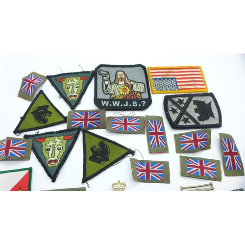 891 - A collection of cap badges, cloth badges, pin badges, etc., including a WWII medal