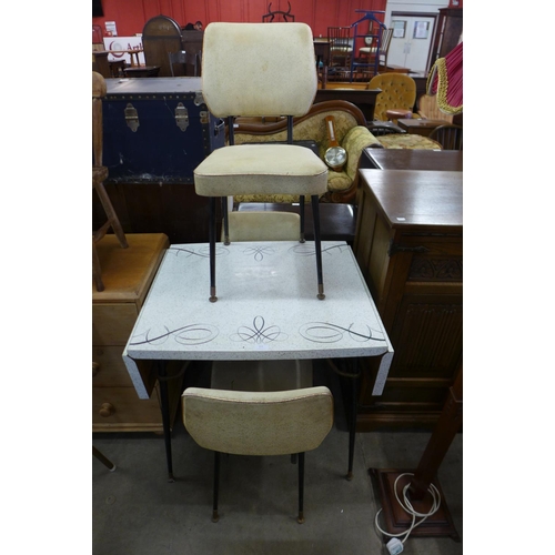 319 - A Formica drop leaf kitchen table and three chairs