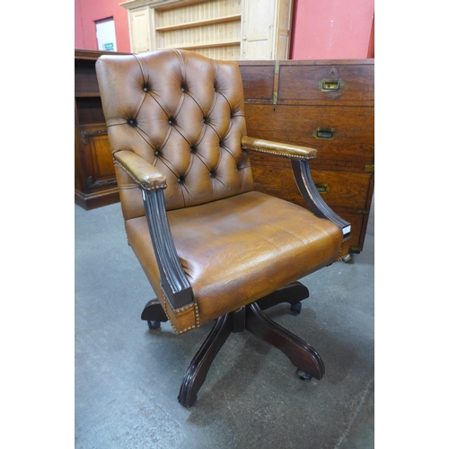 88 - A mahogany and brown leather upholstered revolving desk chair