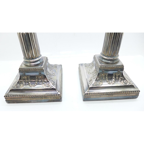 861 - A pair of silver candlesticks of reeded columnar form, with Corinthian tops, each on a square beaded... 