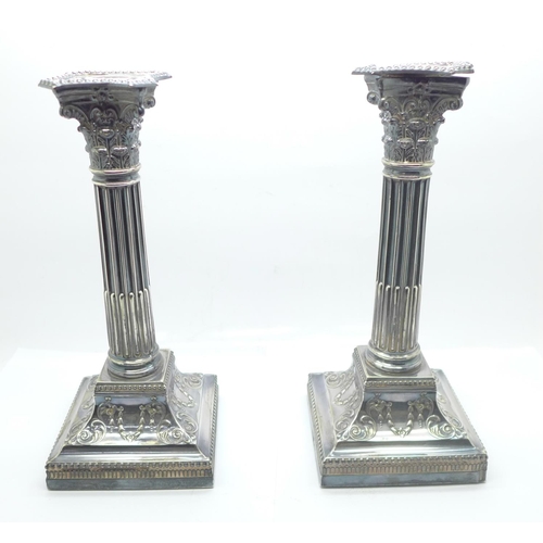 861 - A pair of silver candlesticks of reeded columnar form, with Corinthian tops, each on a square beaded... 