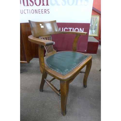 84 - An early 20th Century oak and green leather desk chair