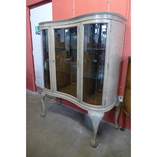 85 - A Queen Anne style bleached walnut serpentine front display cabinet, 152cms h, 130cms w, 50cms d