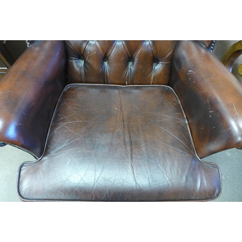 250 - A chestnut brown leather Chesterfield wingback armchair