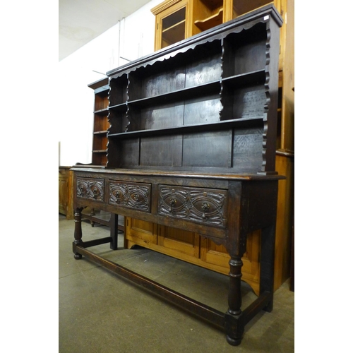 74 - A 17th Century carved oak dresser base, with later Delft rack, 170cms h, 167cms w, 48cms d