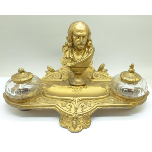 658 - A c.1900 metal inkstand with two glass inkwells, one top a/f, mounted with a bust marked Cornelle