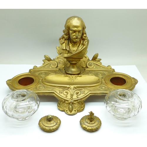 658 - A c.1900 metal inkstand with two glass inkwells, one top a/f, mounted with a bust marked Cornelle