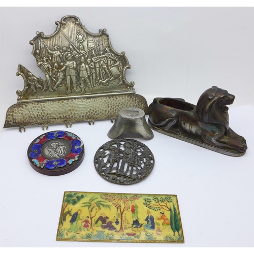 669 - A painted faux ivory plaque, a metal lion pin cushion, Chinese weight, etc.