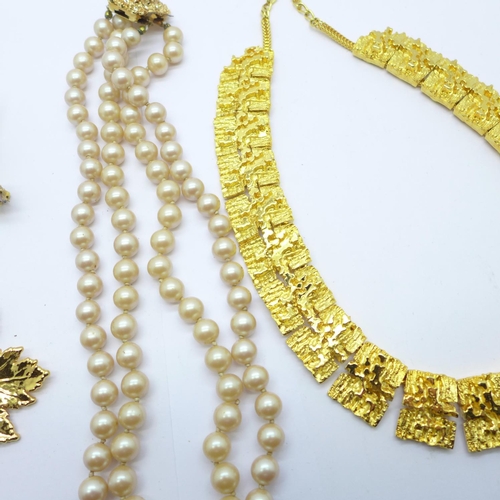 862 - A gilt metal collarette, a double strand faux pearl necklace, a bird brooch and a leaf brooch