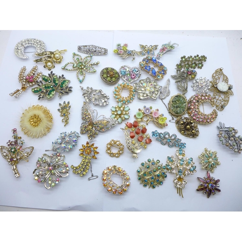 947 - A box containing approximately forty vintage costume brooches