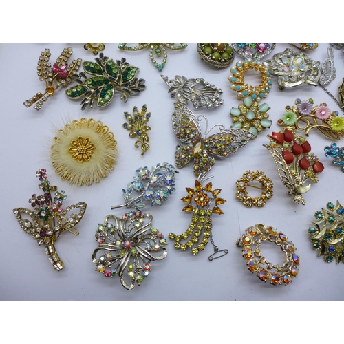 947 - A box containing approximately forty vintage costume brooches